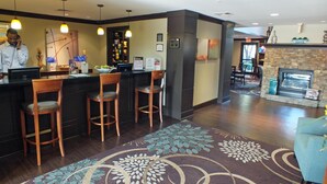 A hotel lobby with a bar area, seating, a fireplace, and a reception desk.