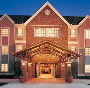 A large brick building with a prominent entrance, multiple windows, and a stone facade.