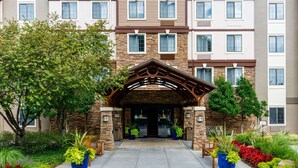 A multi-story hotel with a stone facade, a covered entrance, and potted plants at the entrance. - Sonesta ES Suites Atlanta - Perimeter Center (Atlanta)