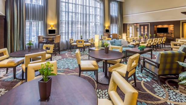 A hotel lobby with a large seating area, multiple tables, and a television. - Sonesta ES Suites Atlanta - Perimeter Center (Atlanta)