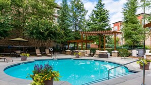 A swimming pool with a pergola, lounge chairs, and potted plants. - Sonesta ES Suites Atlanta - Perimeter Center (Atlanta)