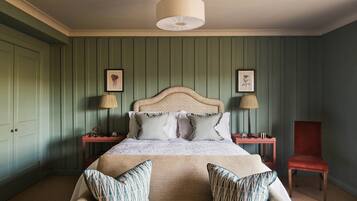 A bedroom with a bed, two nightstands, a red chair, and a green wall.