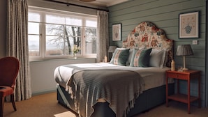 Un dormitorio con una cama grande, una mesita de noche, una silla y una ventana con cortinas.