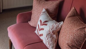 Un sofá rojo con cojines estampados, un asiento junto a la ventana con vistas, y un radiador debajo.