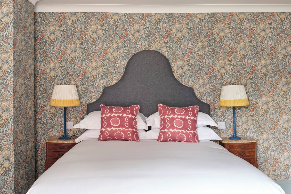 A neatly made bed with two pillows, a dark headboard, and two bedside lamps.