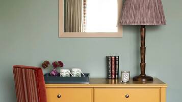 A desk with a mirror, a lamp, and decorative items.