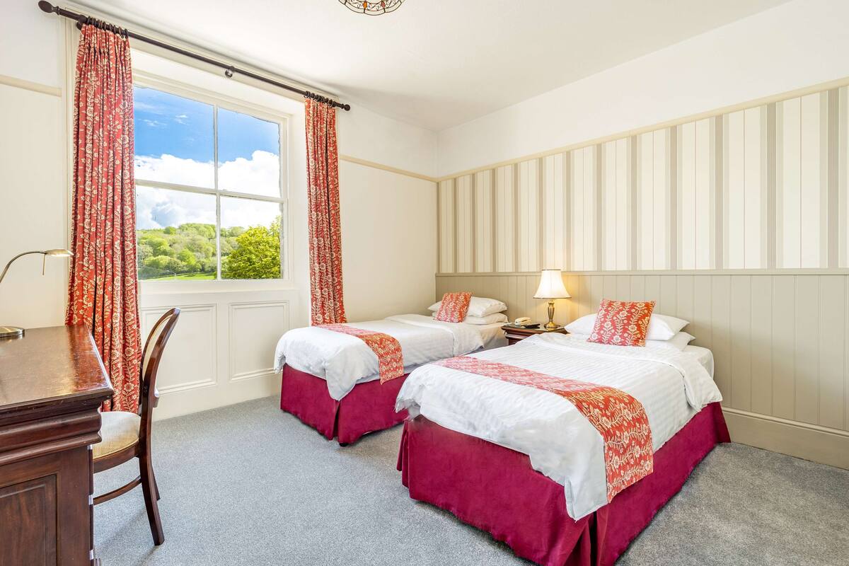 Une chambre d’hôtel avec deux lits, un bureau et une chaise.