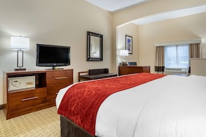 Een hotelkamer met een groot bed, een televisie, een bureau en een dressoir.