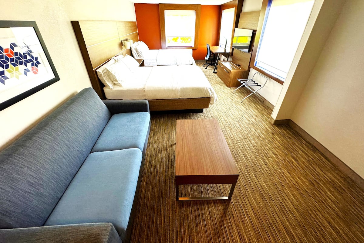 Ein Hotelzimmer mit einem Bett, einer Couch, einem kleinen Tisch und einem Fernseher.