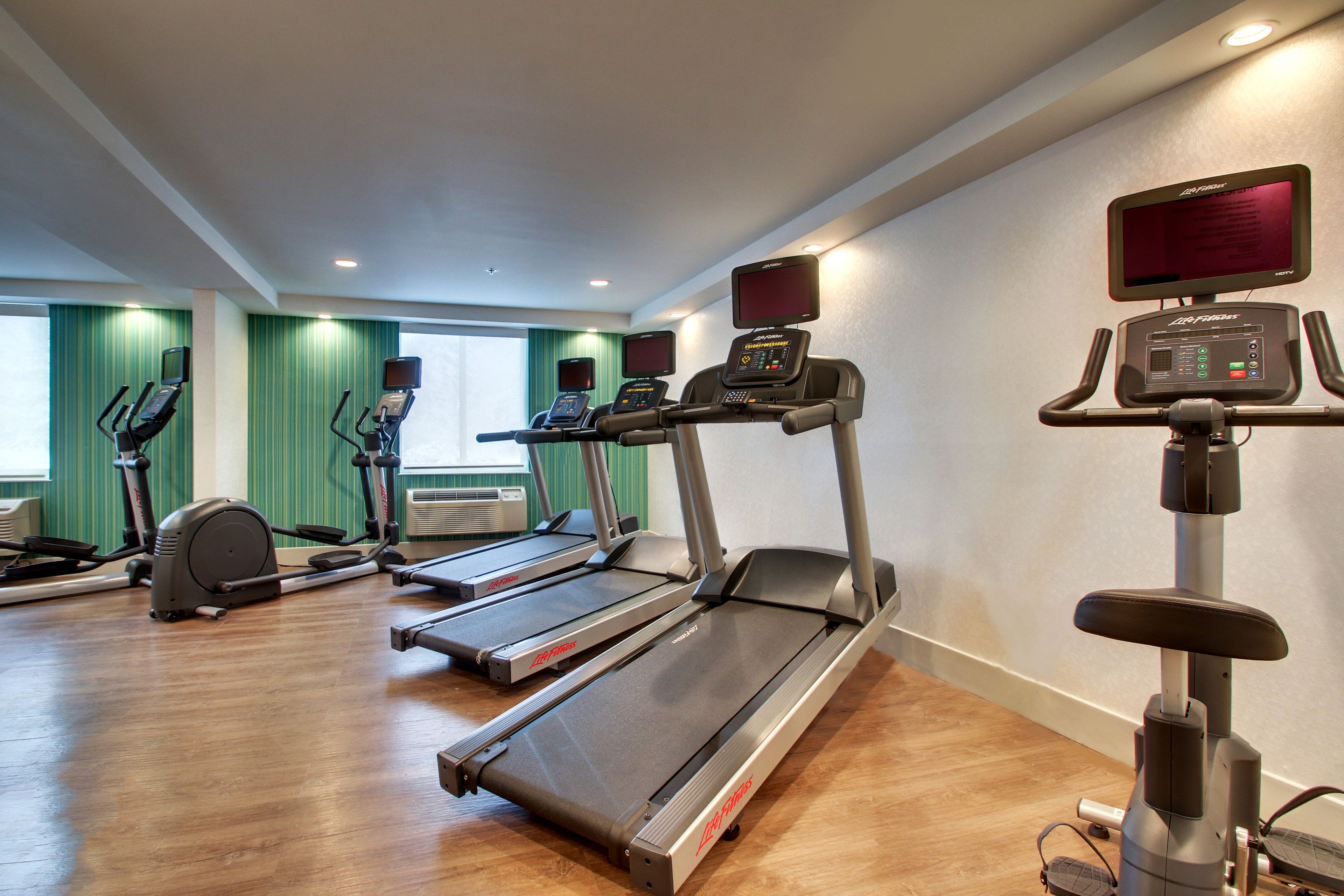 Een sportschool met loopbanden, crosstrainers en een hometrainer.