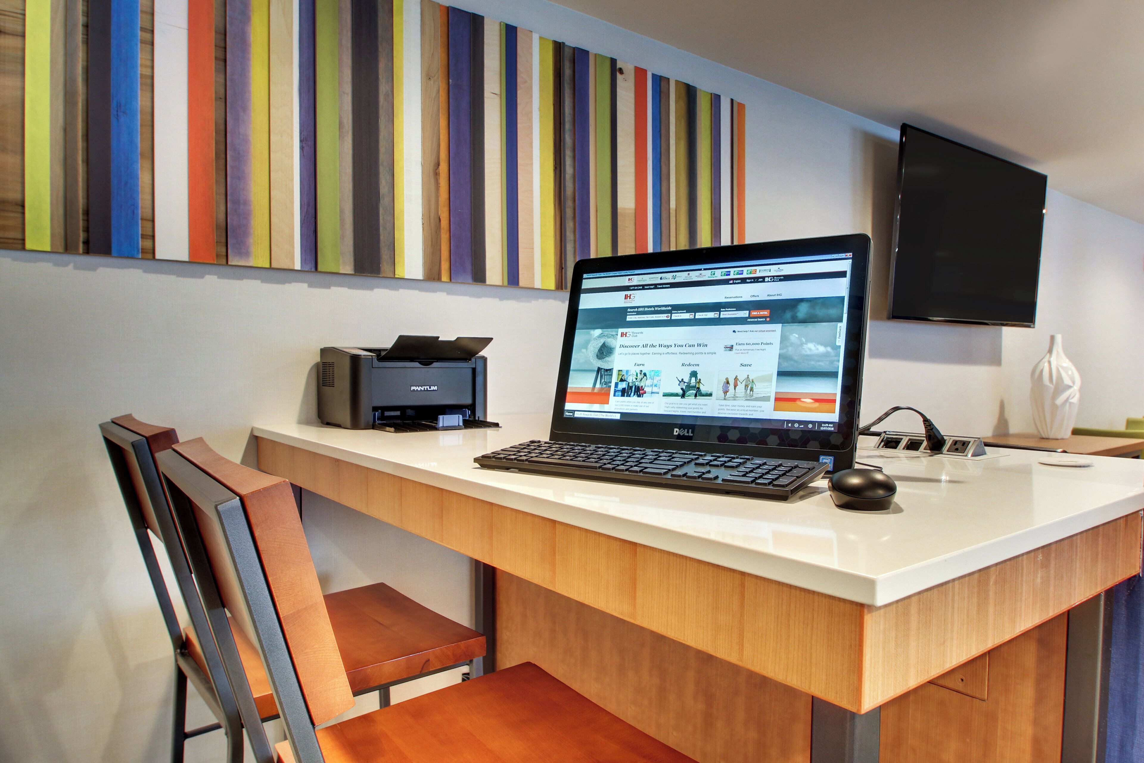 Ein moderner Schreibtisch mit Laptop, Tastatur, Maus und Drucker.