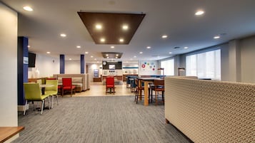 A modern, well-lit indoor space with seating areas, a counter, and a patterned wall.
