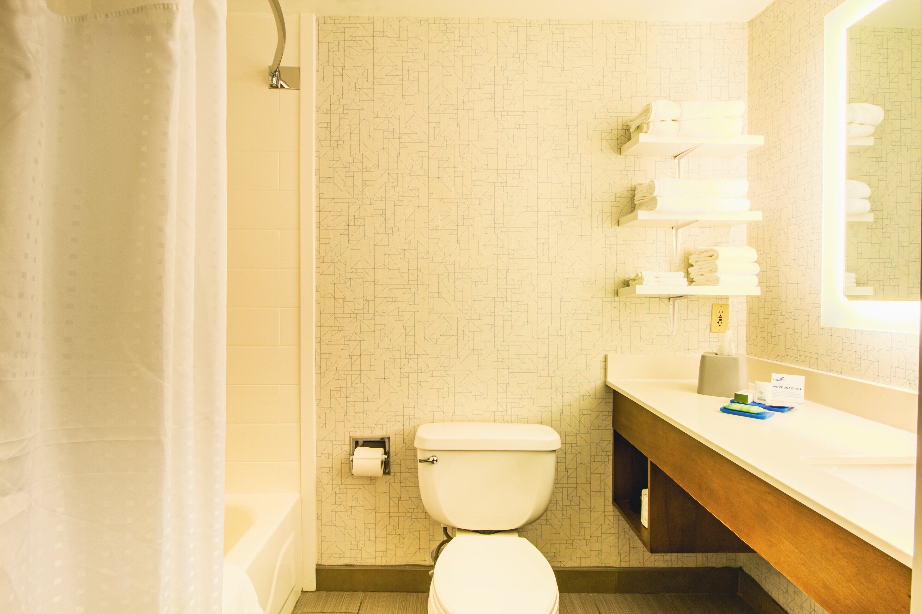 A bathroom with a toilet, a shower curtain, a towel rack, and a sink with a mirror.
