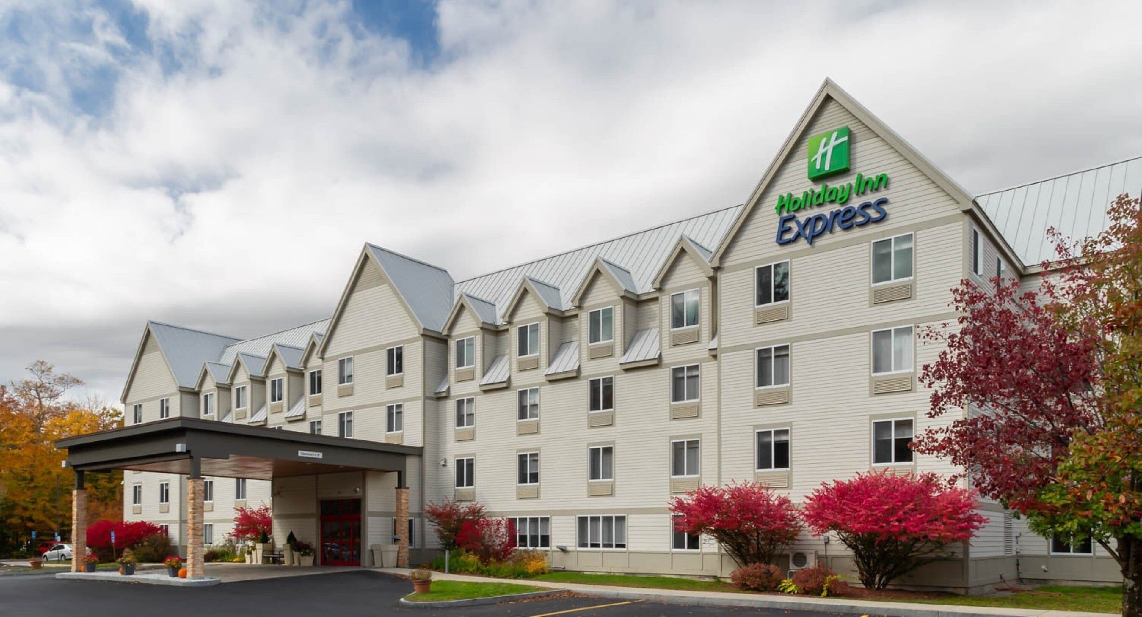 Un hotel Holiday Inn Express con entrada cubierta, varios pisos y estacionamiento.