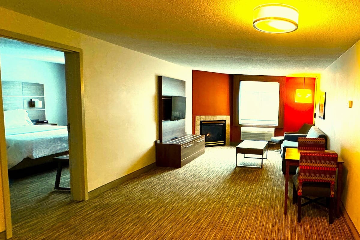Ein Hotelzimmer mit Bett, Fernseher, Kamin und einer Sitzecke mit Tisch und Stühlen.