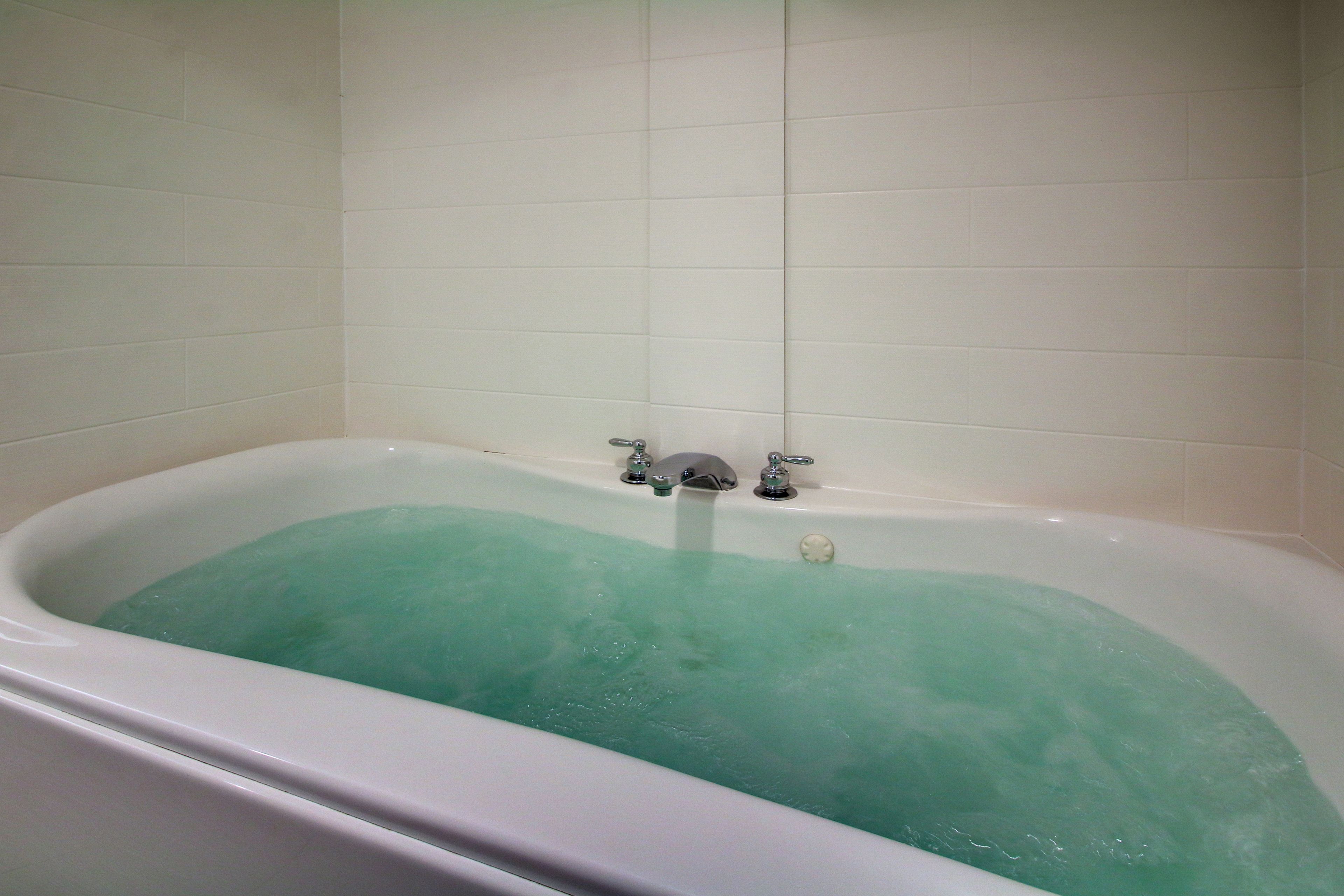 A bathtub with a faucet and a control knob.