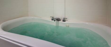 A bathtub with a faucet and a control knob.