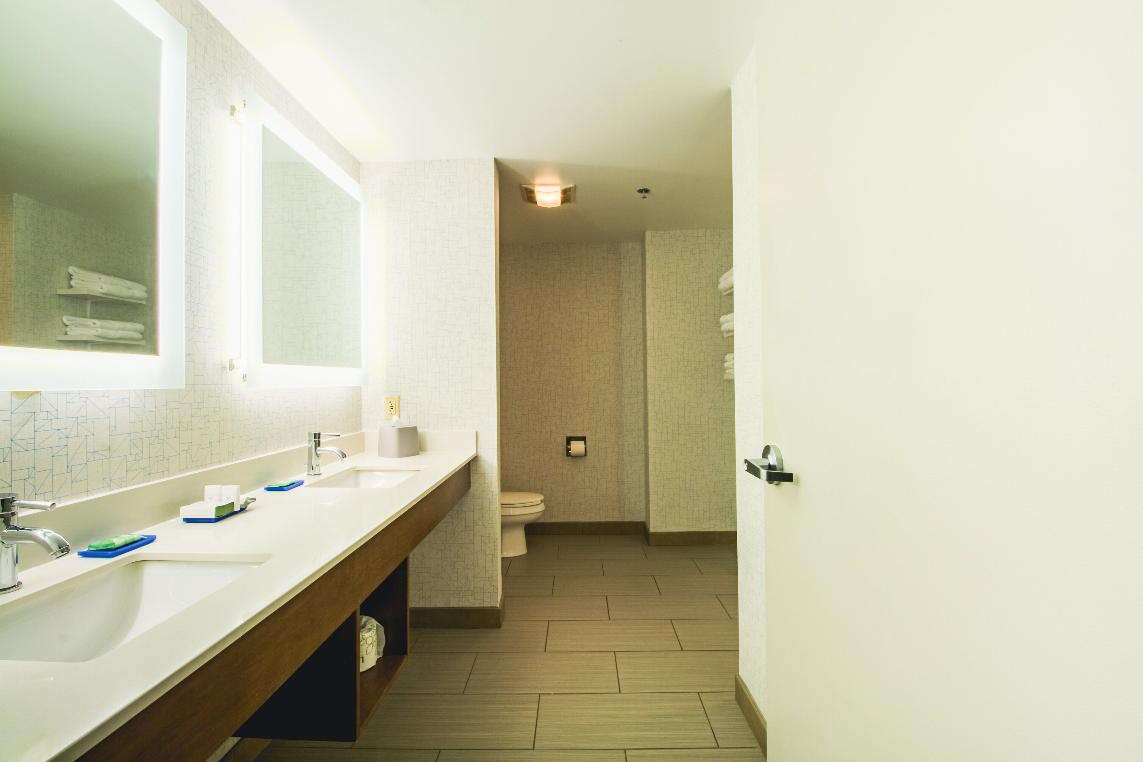 Un baño moderno con un espejo grande, dos lavamanos y un inodoro.