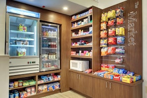A self-service snack and beverage area with refrigerated drinks, microwaves, and a variety of snacks and packaged goods.