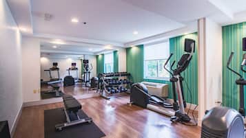 A gym with exercise equipment, a mirror, and a window with curtains.
