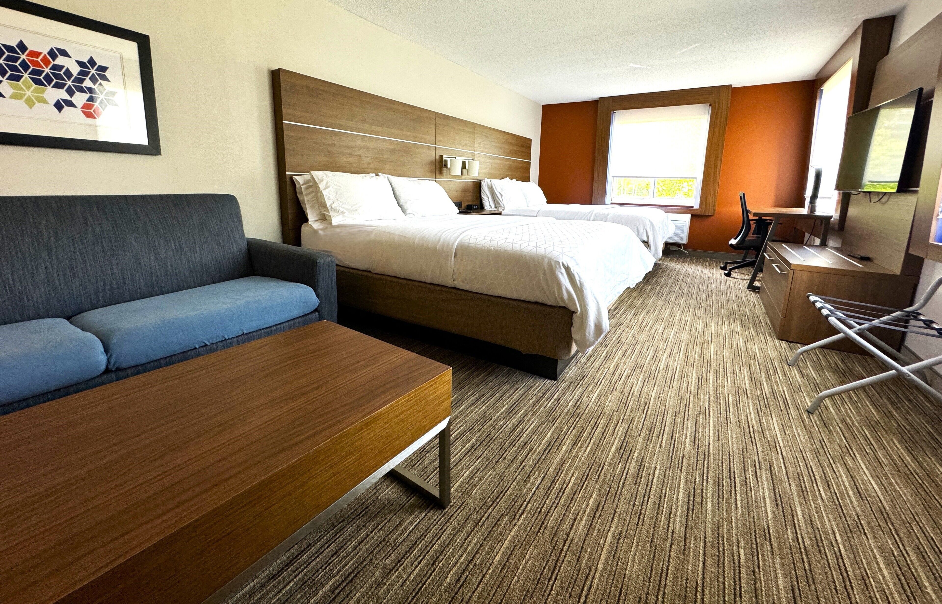 A hotel room with a bed, a sofa, a desk, and a TV.