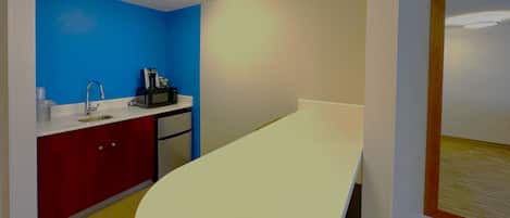 A compact kitchenette with a sink, microwave, and coffee maker.