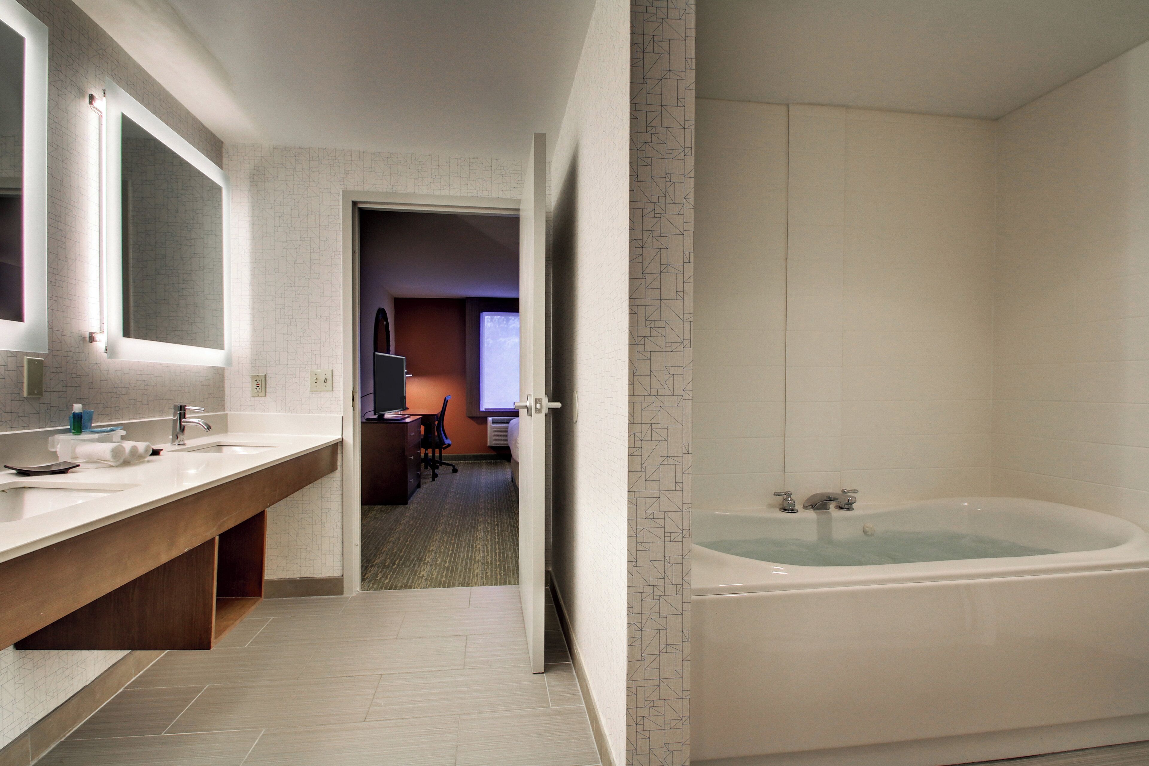 A modern bathroom with a large bathtub, a double sink vanity, and a mirror.