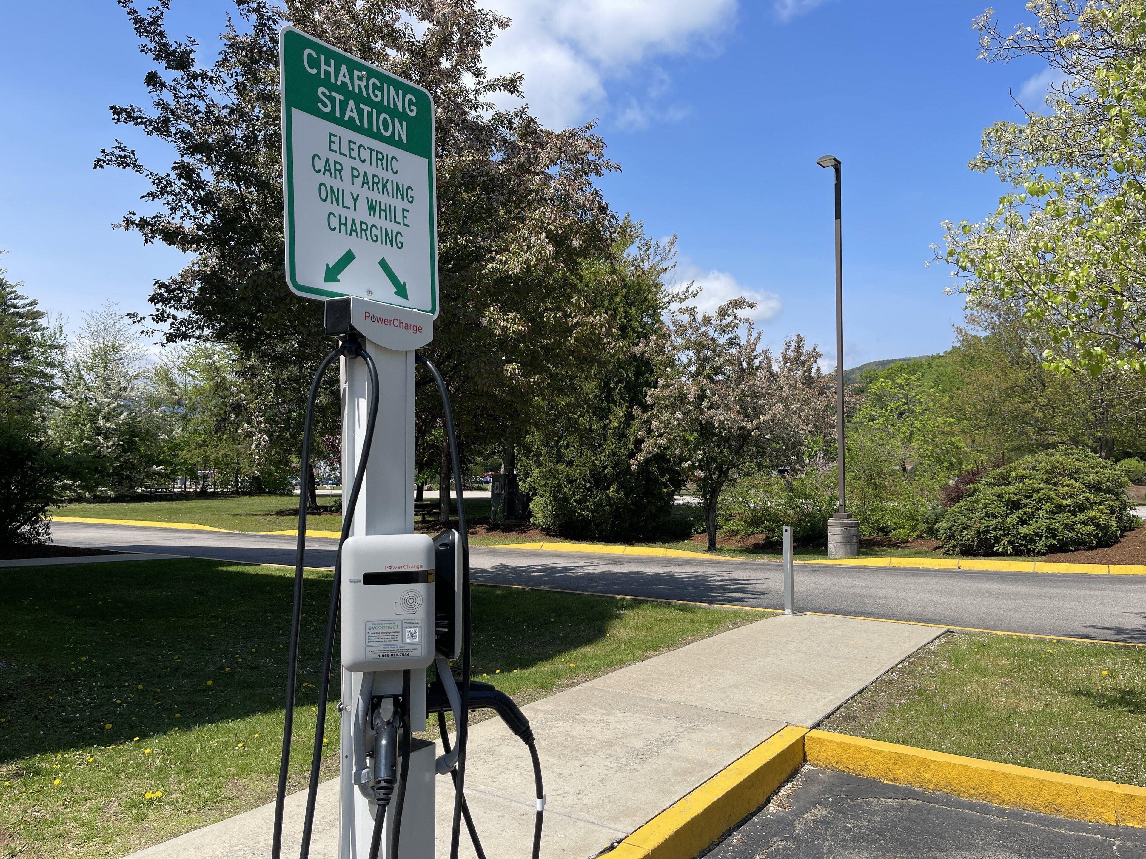 Une borne de recharge avec un panneau indiquant qu’elle est réservée aux véhicules électriques pendant la recharge.