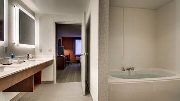 A modern bathroom with a large bathtub, a double sink vanity, and a mirror.