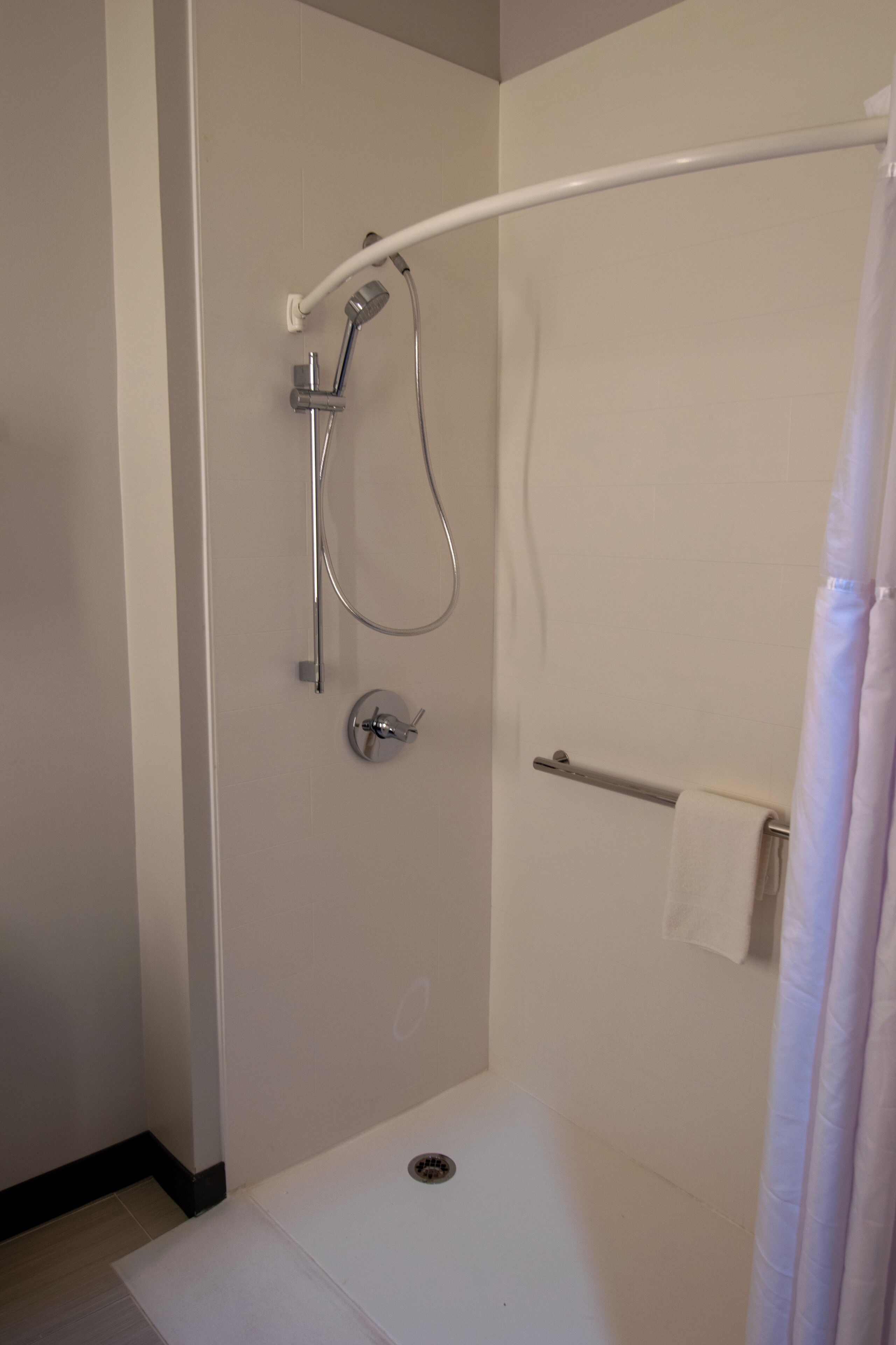 Een moderne douchecel met een handdouche, een wandmengkraan en een handdoekhouder.