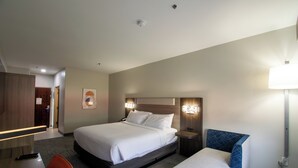 A hotel room with a large bed, bedside tables, a desk with a chair, and a lamp. - Holiday Inn Express and Suites Sulphur Springs by IHG (Sulphur Springs)