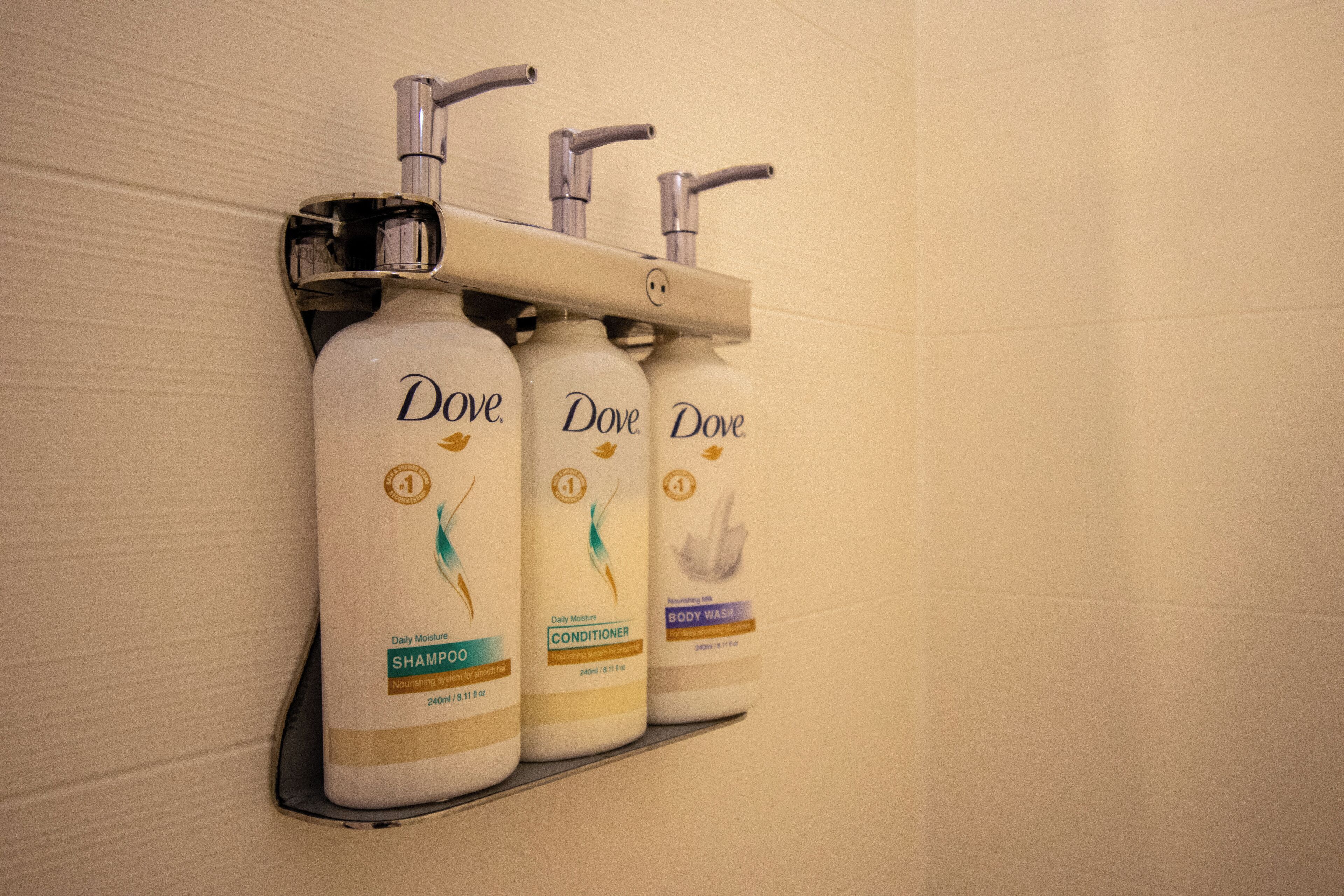 Drei Dove Körperpflegeprodukte auf einem an der Wand befestigten Regal.