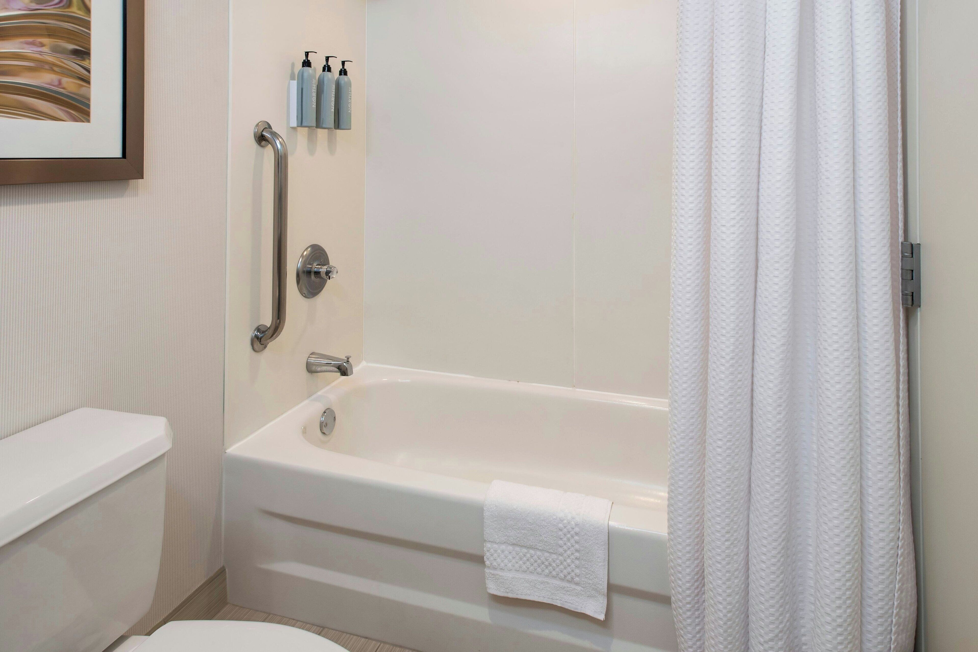 A bathroom with a white bathtub, a toilet, and a shower curtain.