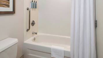 A bathroom with a white bathtub, a toilet, and a shower curtain.