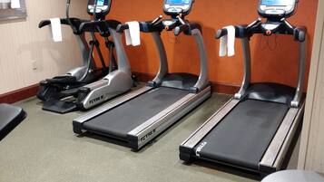 Une salle de sport équipée de trois tapis de course, d’un vélo d’appartement et d’un porte-haltères.