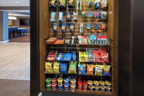 A snack display with various brands and types of chips, snacks, and canned goods.