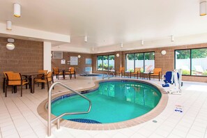 An indoor swimming pool with a tiled floor, surrounded by wooden chairs and tables. - Courtyard Marriott Binghamton (Vestal)