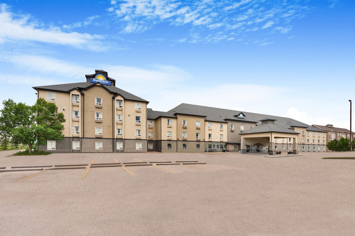 A Days Inn hotel with multiple buildings, a parking lot, and a clear sky.