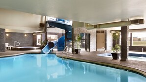 An indoor swimming pool with a blue slide, a small hot tub, and potted plants. - Days Inn by Wyndham Regina (Regina)