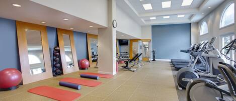 A gym with exercise equipment, mats, and a mirror.
