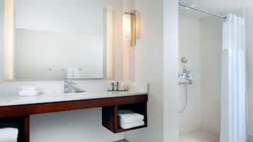 A modern bathroom with a large mirror, a wooden vanity, a shower with a glass door, and a towel rack.