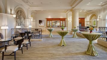 A spacious hotel lobby with multiple seating areas, a bar, and a reception desk.