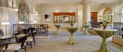 A spacious hotel lobby with multiple seating areas, a bar, and a reception desk.