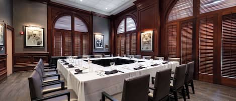 A conference room with a long table, chairs, and framed pictures on the walls.