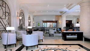 A lobby with a bar area, seating, and a patterned floor. - Hilton Naples (Naples)
