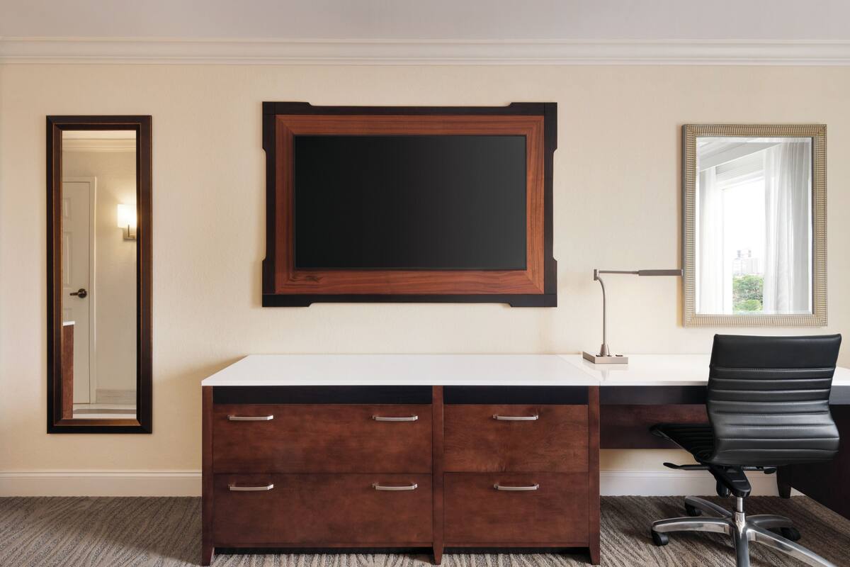 Une chambre d’hôtel avec un grand bureau, un miroir et une porte.