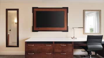 A hotel room with a large desk, a mirror, and a door.