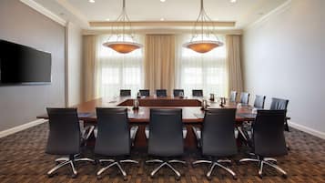 A conference room with a long table, six chairs, and two pendant lights.