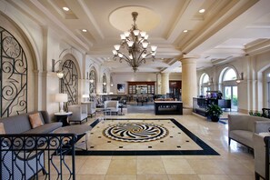 A spacious lobby with a central chandelier, seating areas, and a large decorative rug. - Hilton Naples (Naples)