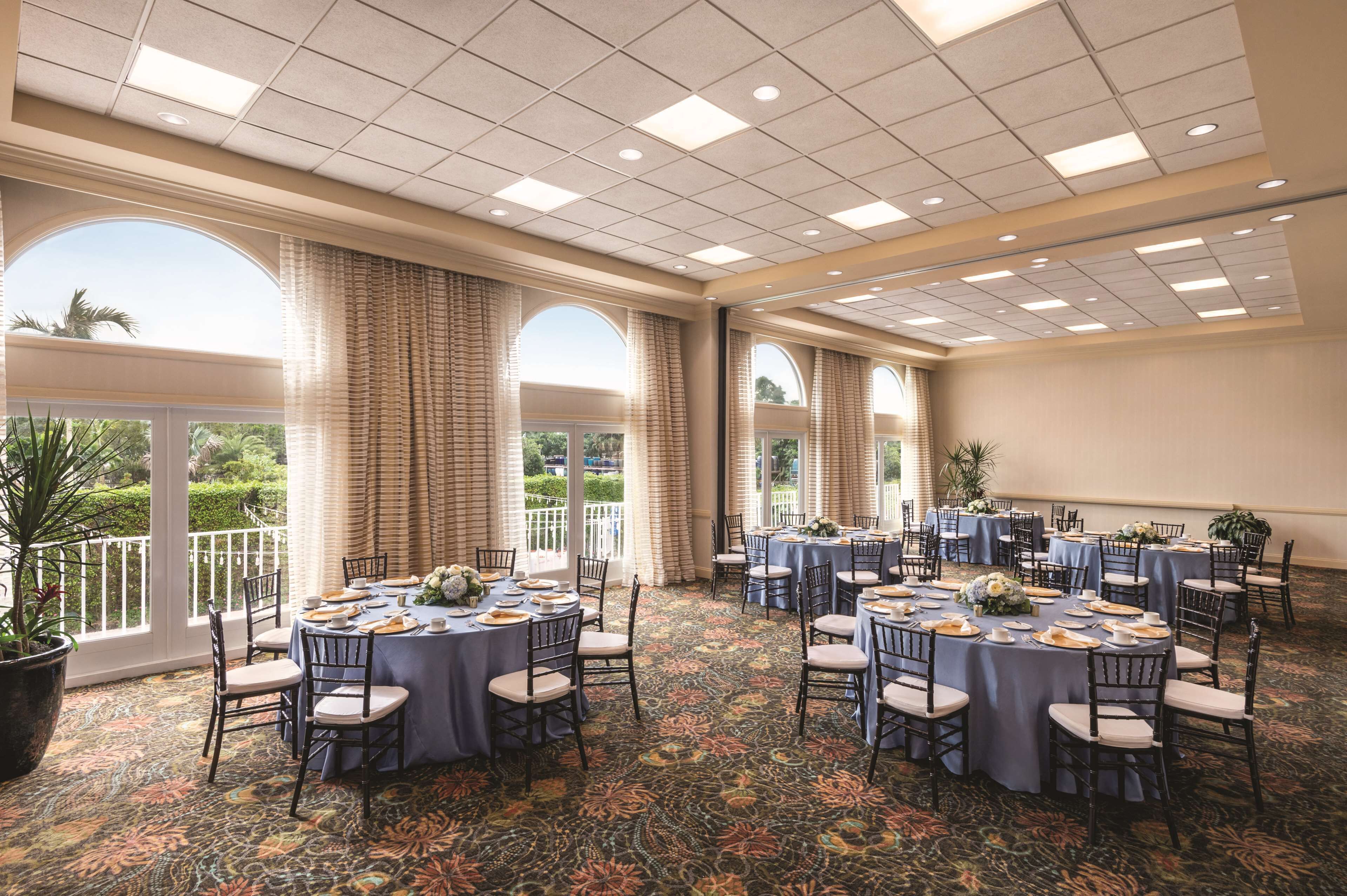 A conference room with round tables, chairs, and a patterned carpet.